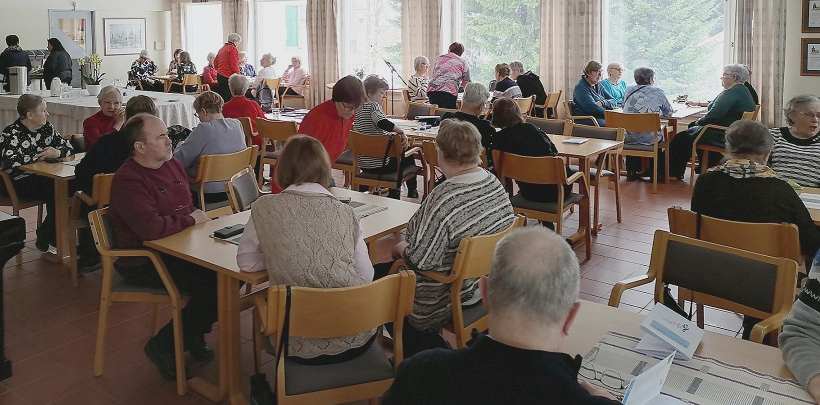 Ihmisiä istumassa pöytien ympärillä.