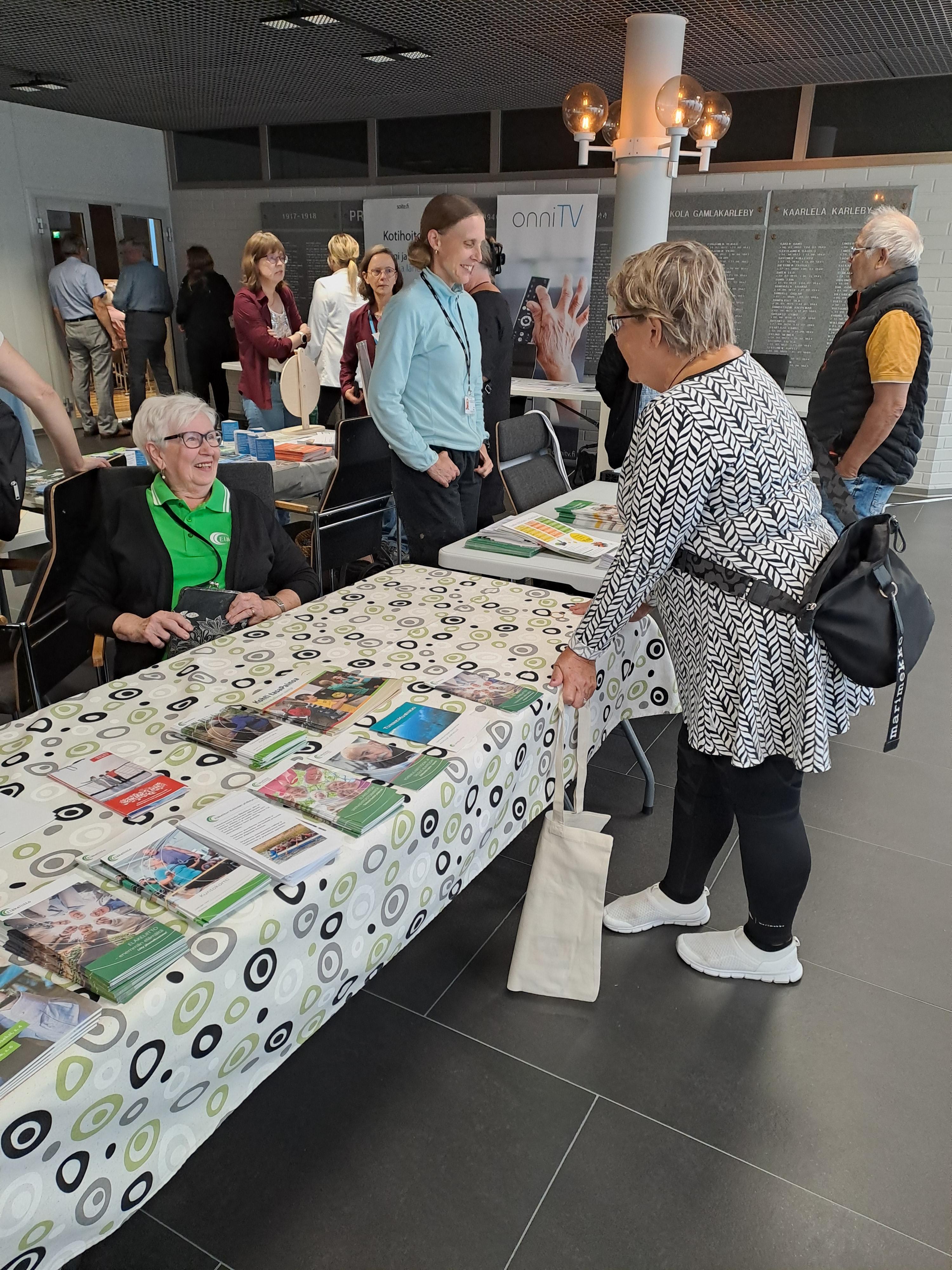 Esittelypöydässä Riitta Anttila ja Tuula Sarell, taustalla ravitsemussuunnitteia Kati Nynäs.