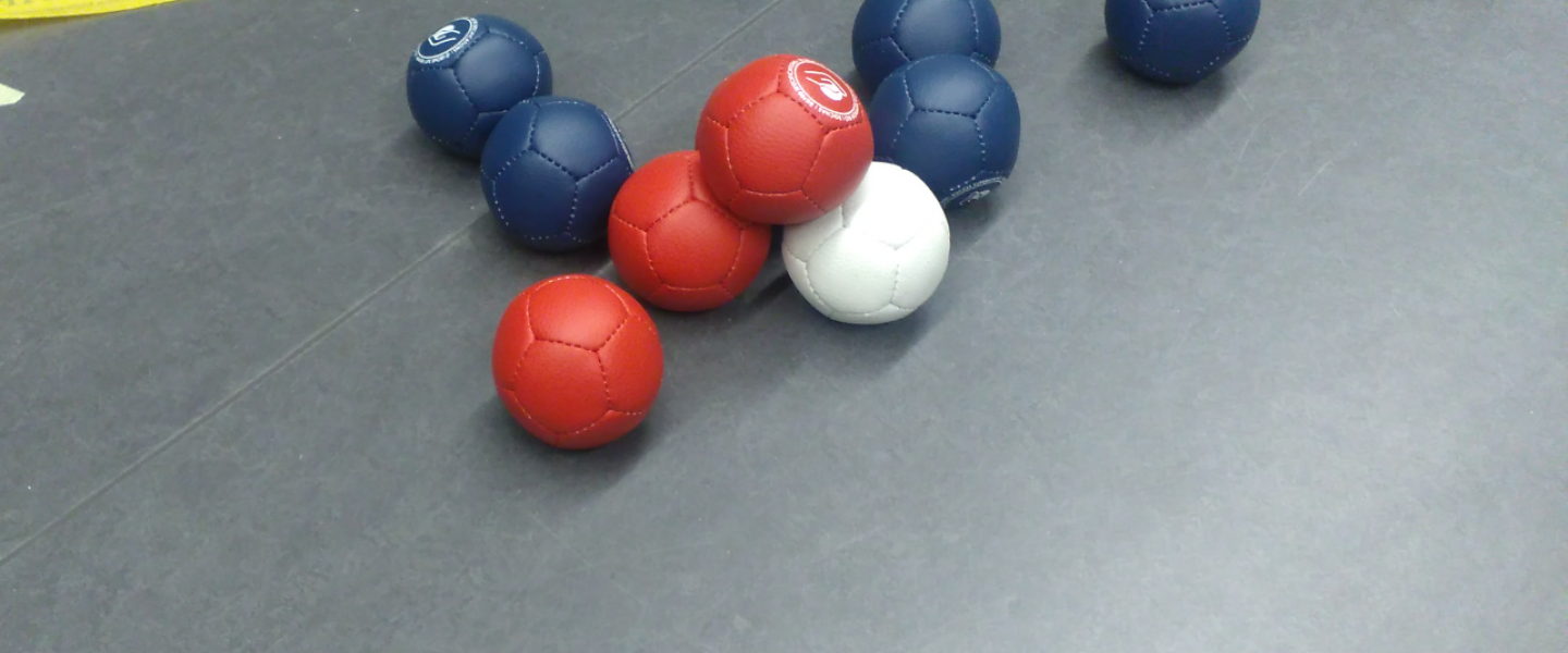 punaisia ja sinisiä boccia-palloja valkoisen ympärillä