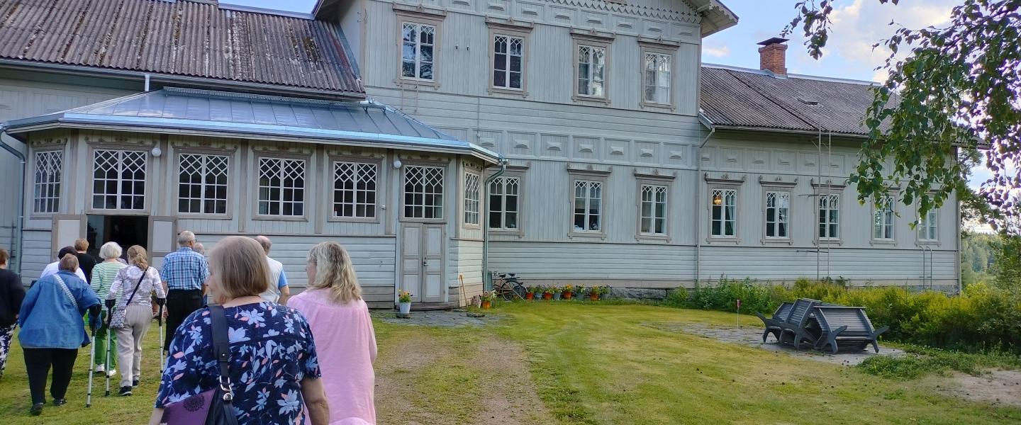 Ihmisiä vanhan talon luona