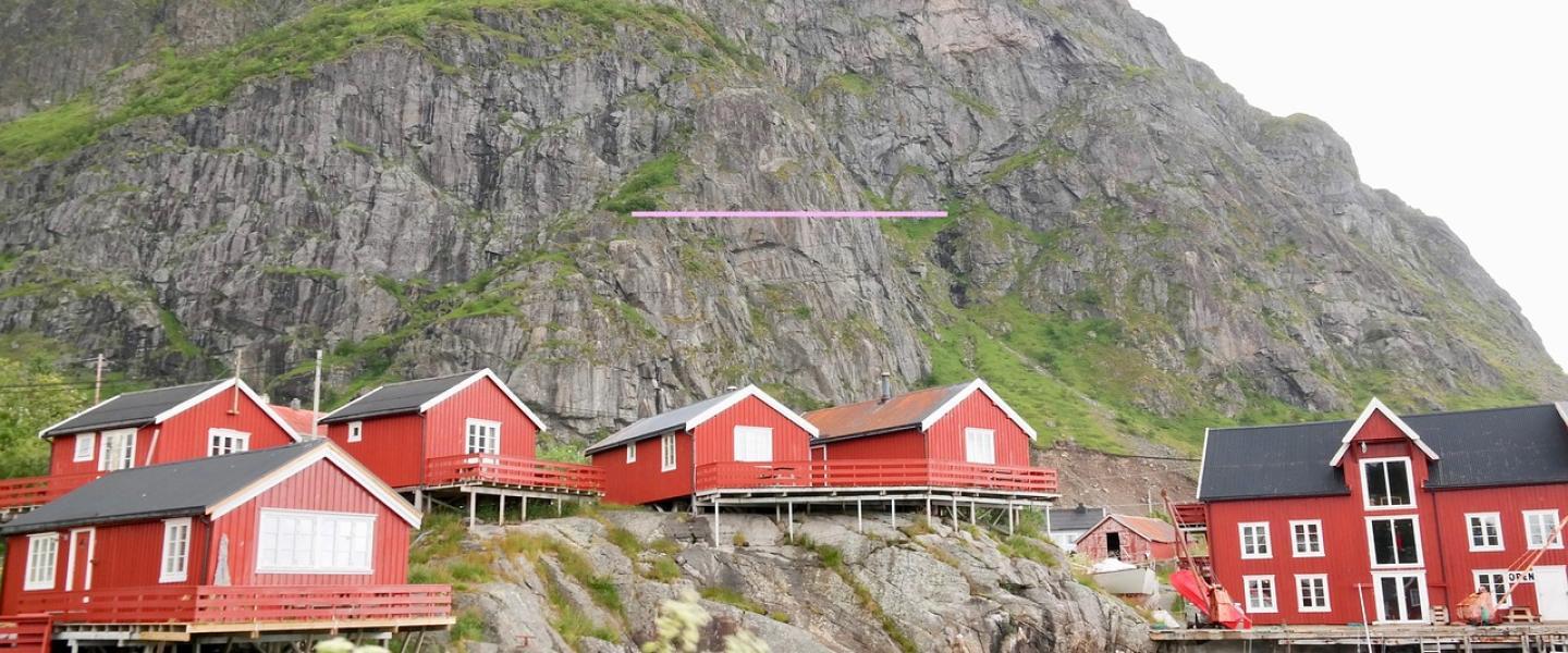 Punaisia puisia rakennuksia kallioisella meren rannalla Norjassa