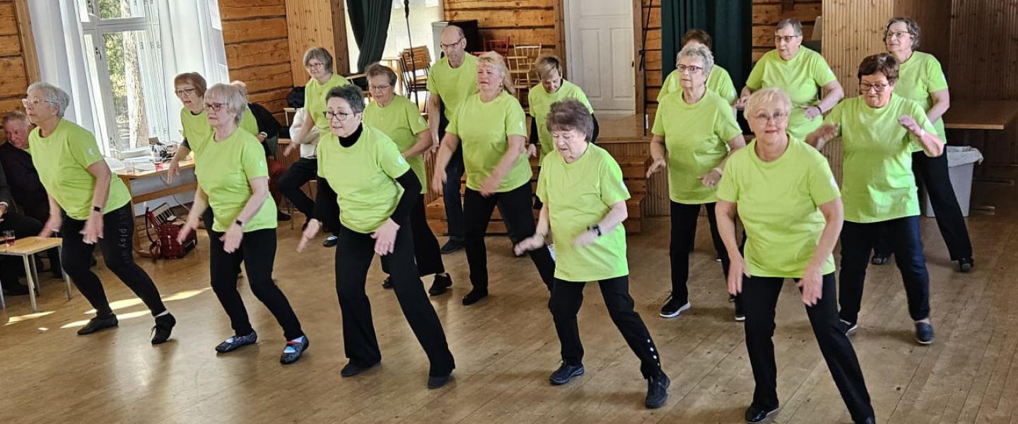 Ryhmä tanssijoita esiintymässä vaaleanvihreät paidat yllään