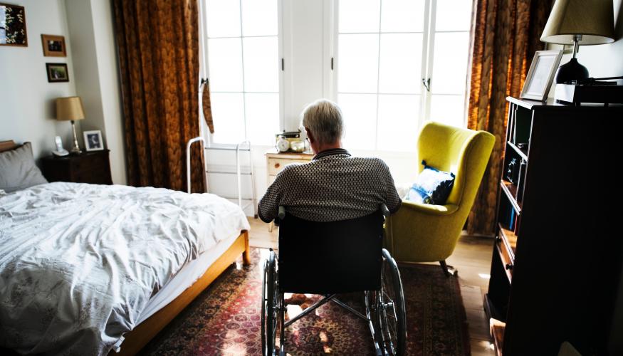 Vanha mies istuu pyörätuolissa huoneessa