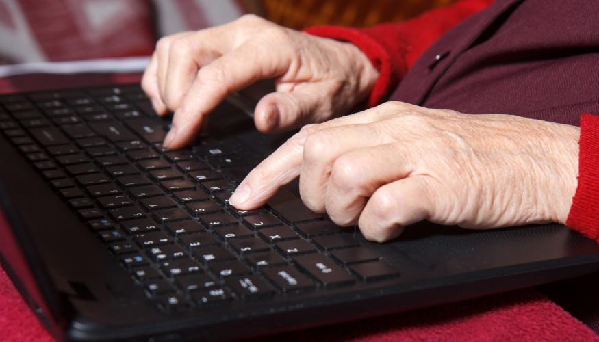 Vanhan naisen kädet tietokoneen näppäimistöllä